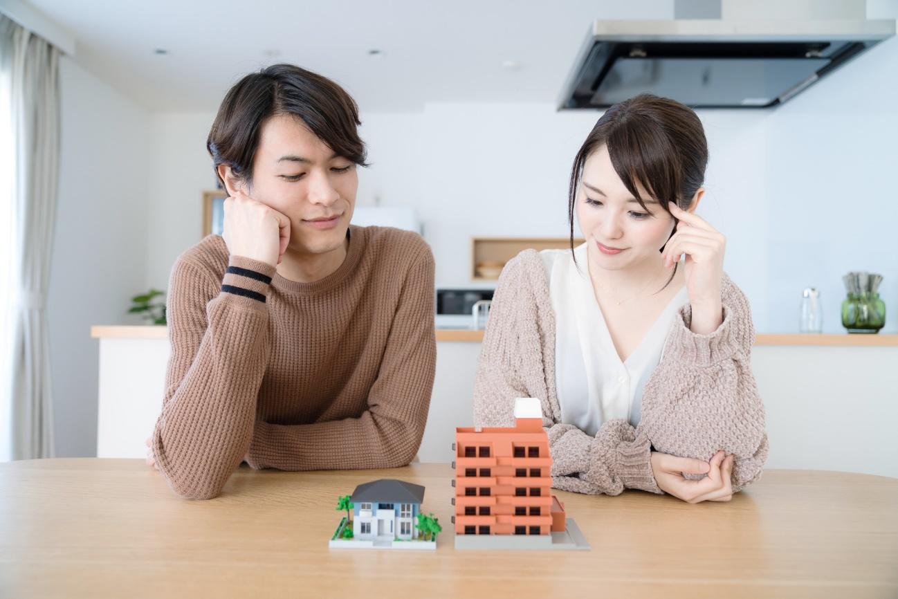 Couple sits at a table, looking at miniature house and apartment models for real estate planning.