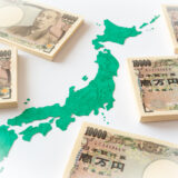 Stacks of Japanese yen banknotes surrounding a green map of Japan, emphasizing money and geography.