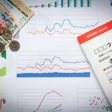 Financial charts and currency on a desk, suggesting market analysis and budgeting