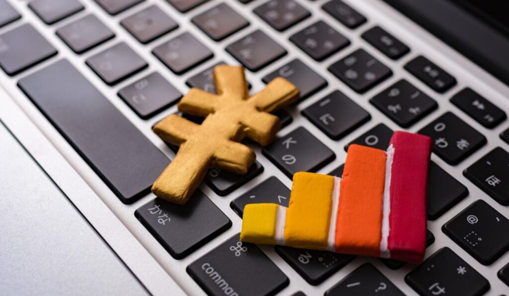 Wooden cross and multicolored bar chart resting on a laptop keyboard, implying data visualization in a tech context.