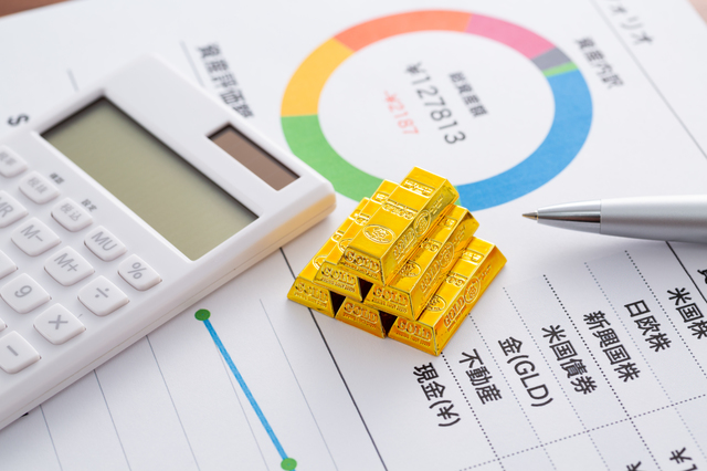 Calculator, gold bullion bars, and a pen on a financial report with a colorful circular chart, suggesting investment analysis.