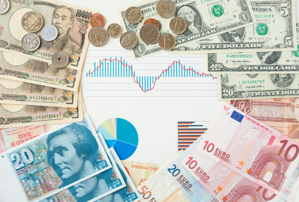 Collage of assorted banknotes and coins surrounding a financial chart with blue bars and a red line.