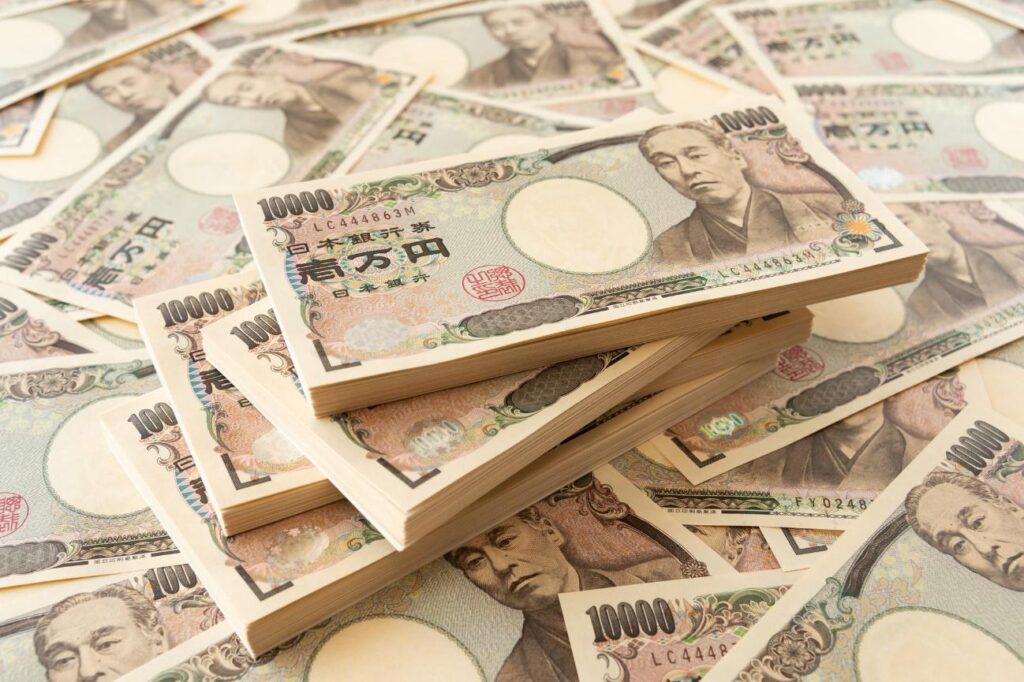 Stacks and scattered 10,000 yen notes featuring Fukuzawa Yukichi, emphasizing wealth imagery on a desk