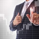 Businessperson in a suit points at a transparent stock chart overlay, illustrating market analysis.